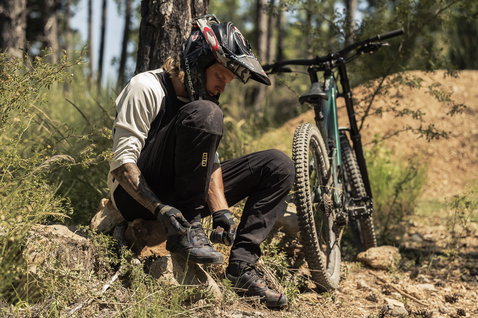 ION Scrub unisex bike pants in black during downhill mountain biking in the forest