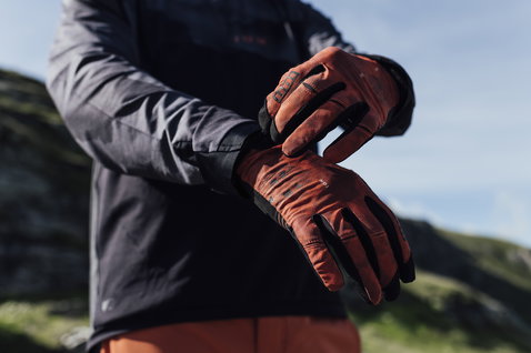 ION Traze Long full-finger bike gloves in burnt orange and black during mountain biking on a mountain trail