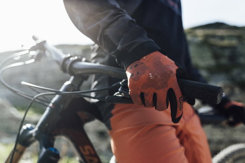 ION Traze Long full-finger bike gloves in rust orange during mountain biking on a rocky trail