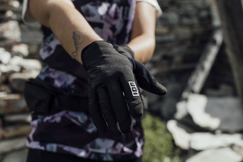 ION Scrub Amp Fahrradhandschuhe in schwarz beim Anziehen im Gelände