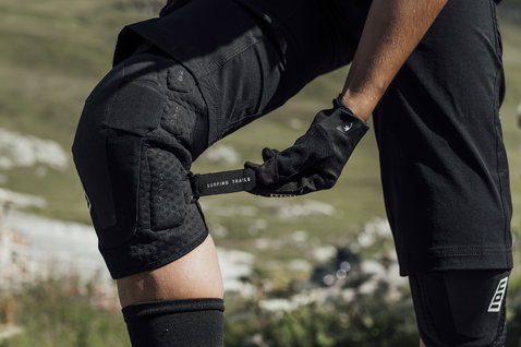 Joelheiras ION Bike K-Lite Zip em preto durante ciclismo de montanha no trilho