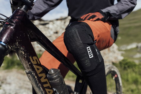 Joelheiras ION K-Lite Zip em preto durante mountain bike num trilho de montanha