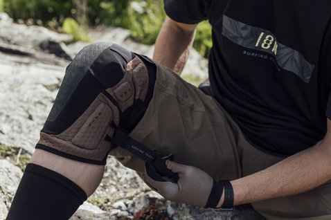 ION K-Lite knee pads being adjusted on rocky outdoor terrain