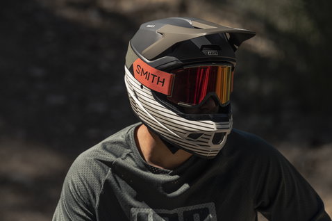 ION Scrub Amp fullface helmet in matte black and taupe worn during mountain biking on a rocky trail