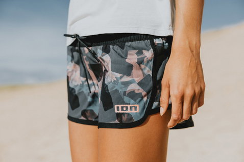 ION Tally women's hotshorts in dark charcoal abstract print worn on a sandy beach