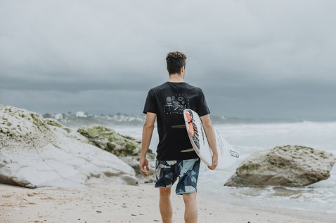 ION Avalon 18" men's boardshorts in navy and teal geometric print during surfing at the beach