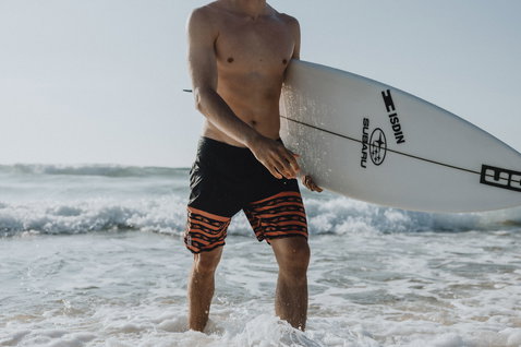 Short de surf ION Slade 19" homme en noir et orange lors du surf à la plage