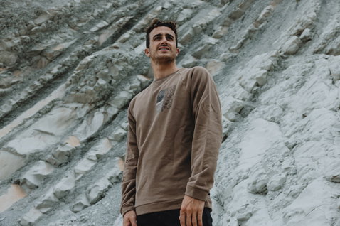 ION Surfing Elements Herren-Sweater in warmem taupe beim Tragen im Freien vor Felswand