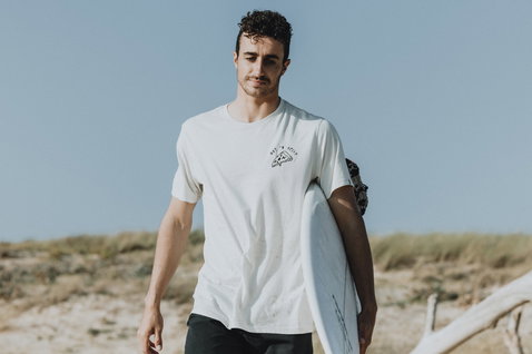 ION Mood Kurzarm-T-Shirt für Herren in off-white beim Strandspaziergang mit Surfboard