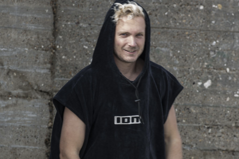 ION Core unisex surf poncho in navy black with hood, worn by a male model outdoors