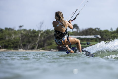 ION Nova seat harness worn during kitesurfing in a tropical lagoon, action lifestyle shot