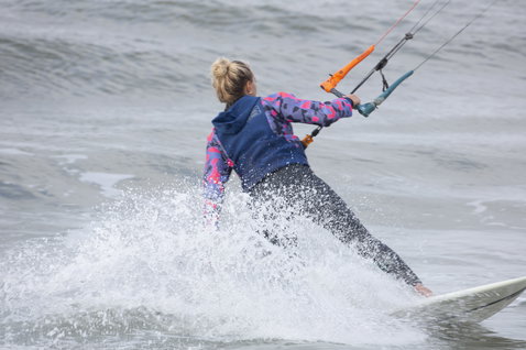 ION Neo Hoody Lite sweat néoprène femme en bleu marine et rose lors d'une session de kitesurf en mer