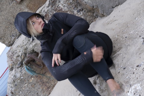 ION Neo Shelter Jacket Amp veste néoprène femme en noir au bord de la côte