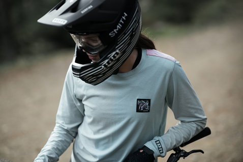 ION Seek Amp LS women cycling jersey in mint green during mountain biking on a forest trail
