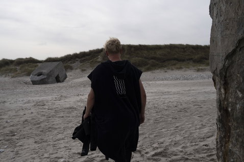 ION Core surf poncho unisex in black worn at the beach coast