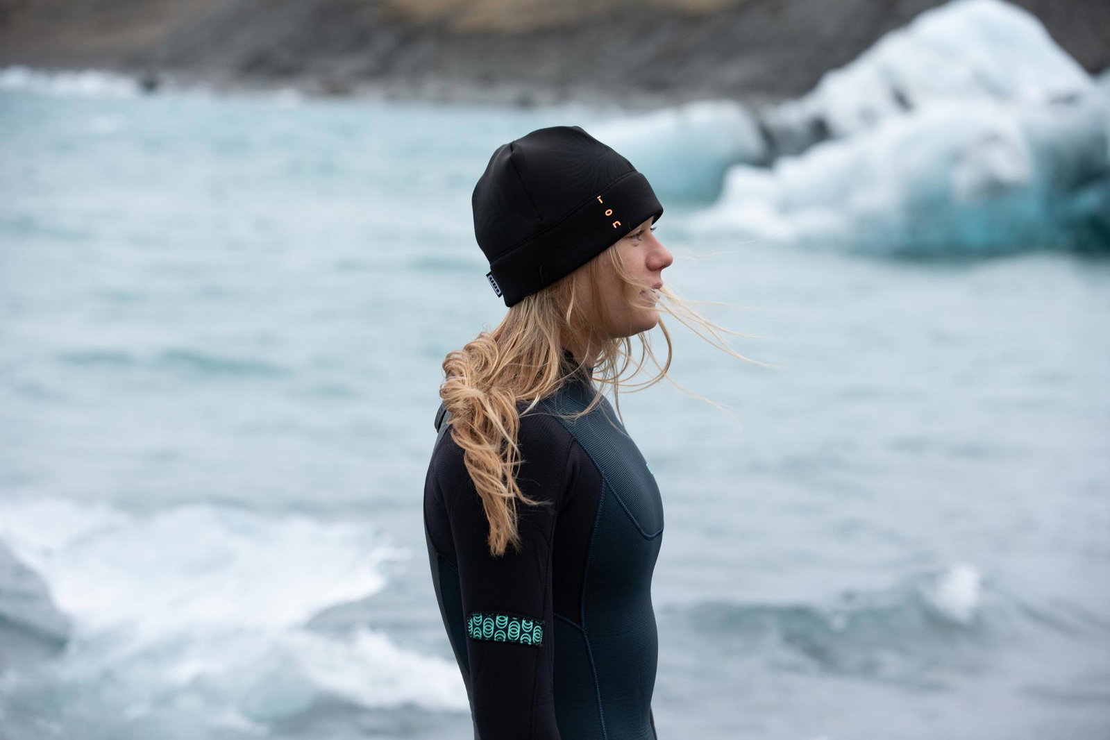 ION Neo Grace bonnet néoprène femme en noir lors d'un sport nautique sur une lagune glaciaire