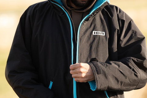 ION Storm Coat changing robe in black and teal worn outdoors after a watersports session