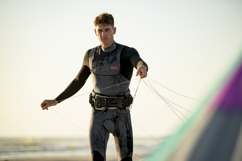 ION Seek Amp 4/3mm front-zip fullsuit in charcoal black during kitesurfing on the beach