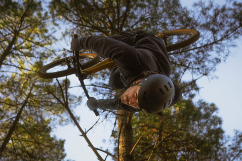 Casco ION Bike Seek durante un salto BMX nel bosco, indossato da un rider in un trick aereo