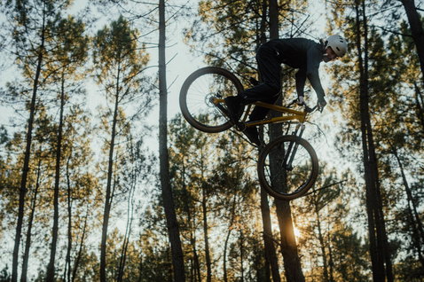 Casco ION Bike Seek in bianco durante un salto dirt jump in mountain bike in una pineta