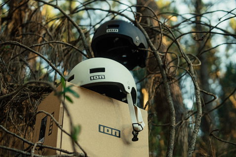 Casco bici ION Seek in crema e nero in ambiente forestale con confezione ION