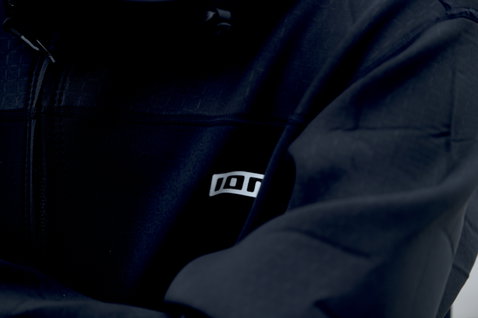 Veste coupe-vent ION Neo Shelter Core homme en noir – détail logo et poche poitrine