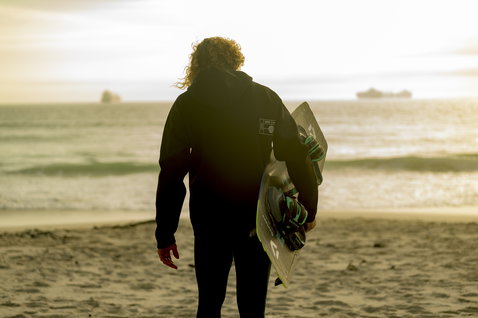 ION Neo Hoody Lite sweat néoprène en noir lors du kitesurf sur la plage au coucher du soleil