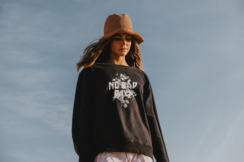 ION No Bad Days Damen-Sweater in charcoal mit Grafik-Print, getragen bei einem Outdoor-Lifestyle-Shooting unter blauem Himmel