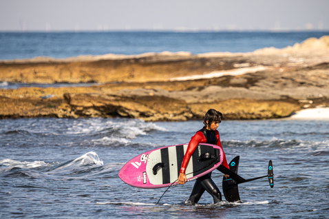 ION Capture 4/3mm back-zip junior fullsuit in black and red during foiling at the ocean