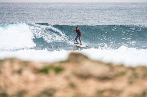 ION Capture 4/3mm back-zip junior fullsuit in dark teal and burgundy during wave surfing in the ocean