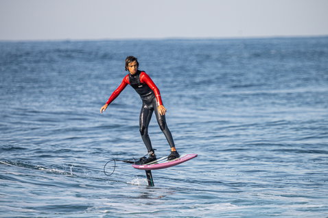 ION Capture 4/3mm front-zip fullsuit junior during foiling on the ocean in black and red