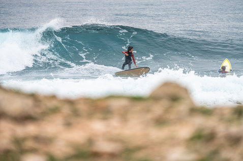 ION Capture 5/4mm back-zip fullsuit junior in black and red during wave riding in the ocean
