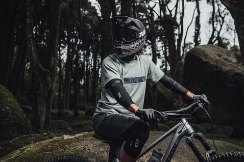 ION E-Sleeve Amp elbow pads in black during mountain biking in forest trail