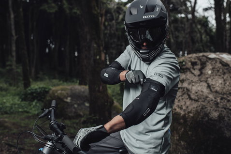 ION E-Sleeve Amp elbow pads in black during mountain biking in a forest
