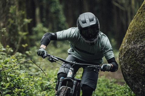 ION E-Sleeve Amp elbow pads in black during mountain biking in forest trail