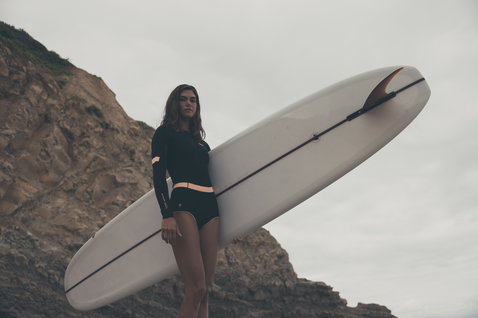 ION Amaze Hot Shorty 1.5mm front-zip shorty wetsuit in black and peach during surfing at the coast