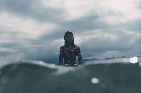 ION Amaze 1.5mm front-zip long-sleeve shorty wetsuit in dark teal and coral during wave riding in the ocean