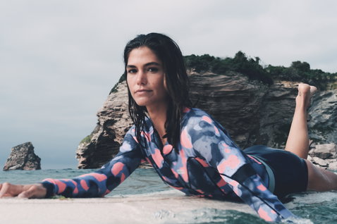 ION Amaze Hot Shorty 1.5mm front-zip long-sleeve shorty wetsuit in dark navy with coral and blue print during wave riding