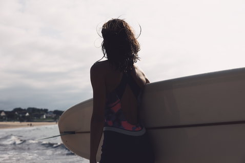 ION Amaze Shorty Crossback 1.5mm pull-on shorty wetsuit in dark charcoal and coral during surfing at the beach