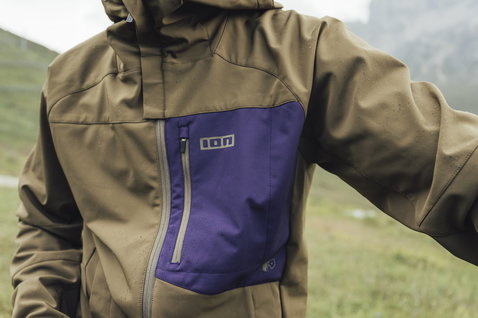 ION Shelter 2L Softshell Mountainbike-Jacke in olivbraun und lila beim Biken in den Bergen