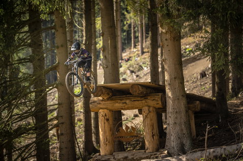 ION Bike Scrub SS youth short-sleeve jersey during mountain biking on a wooden trail feature in forest