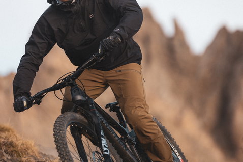 ION Shelter Anorak 2.5L cycling jacket in black during mountain biking on a rocky trail