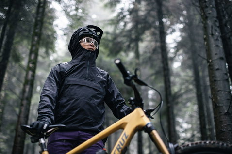 ION Bike Shelter Anorak 2.5L cycling jacket during mountain biking in a rainy forest in black