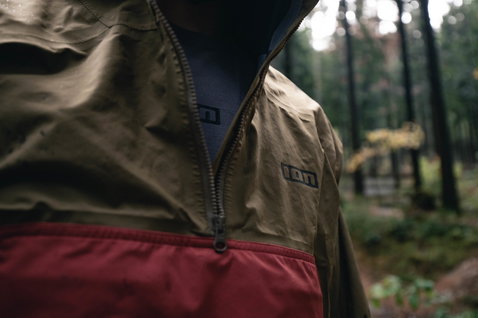 ION Bike Shelter Anorak 2.5L cycling jacket in olive and dark red during mountain biking in the forest