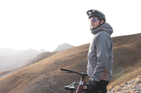ION Bike Shelter Hybrid Padded MTB-Jacke in hellgrau beim Mountainbiken in den Bergen
