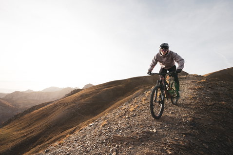 ION Shelter Hybrid Padded Jacke in hellem taupe beim Mountainbiken auf einem Alpinen Bergkamm