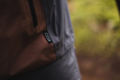 ION Bike Shelter 3L Herren Fahrradjacke in dunkelgrau und braun – Taschendetail beim Mountainbiken