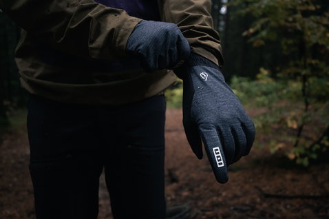 ION Shelter Amp Hybrid Padded full-finger bike gloves in charcoal being put on in an autumn forest