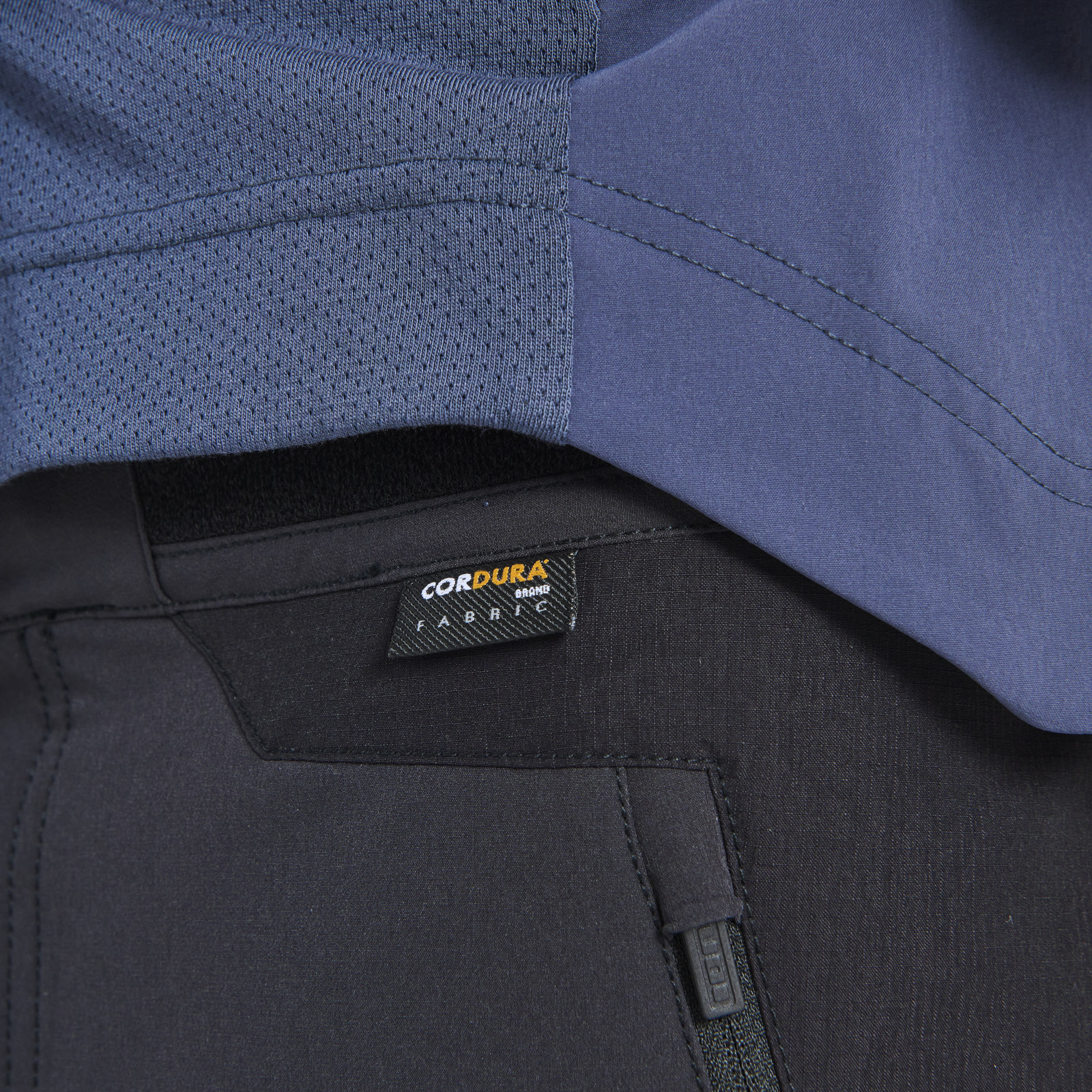 ION Bike Scrub Amp BAT cycling pants detail showing Cordura fabric label and mesh ventilation panel in black and blue-grey