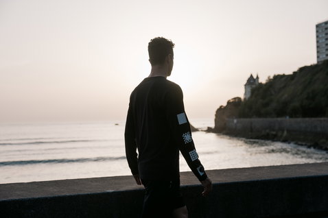 ION Bike Vibes LS men's long-sleeve tee in black worn at the coast during golden hour